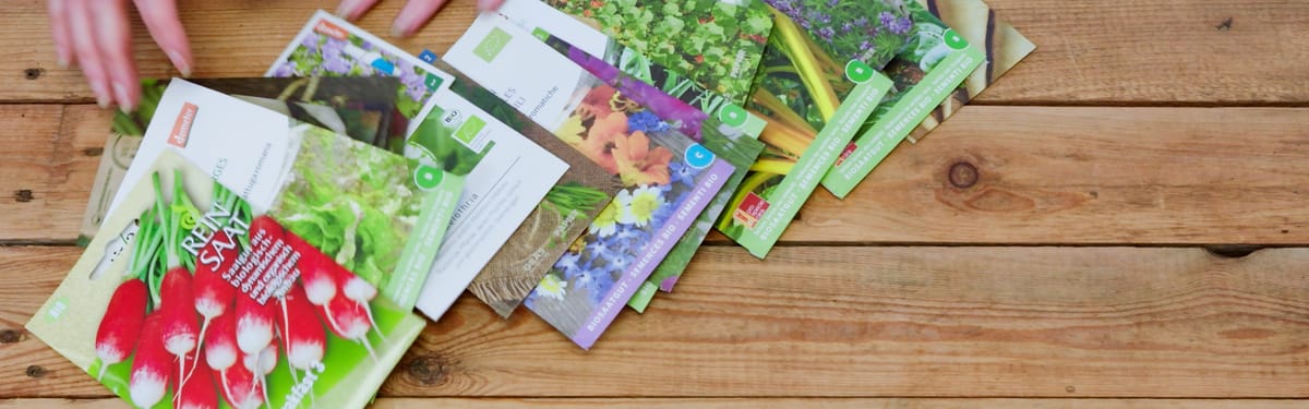 Einige Tütchen Saatgut auf einem Holztisch